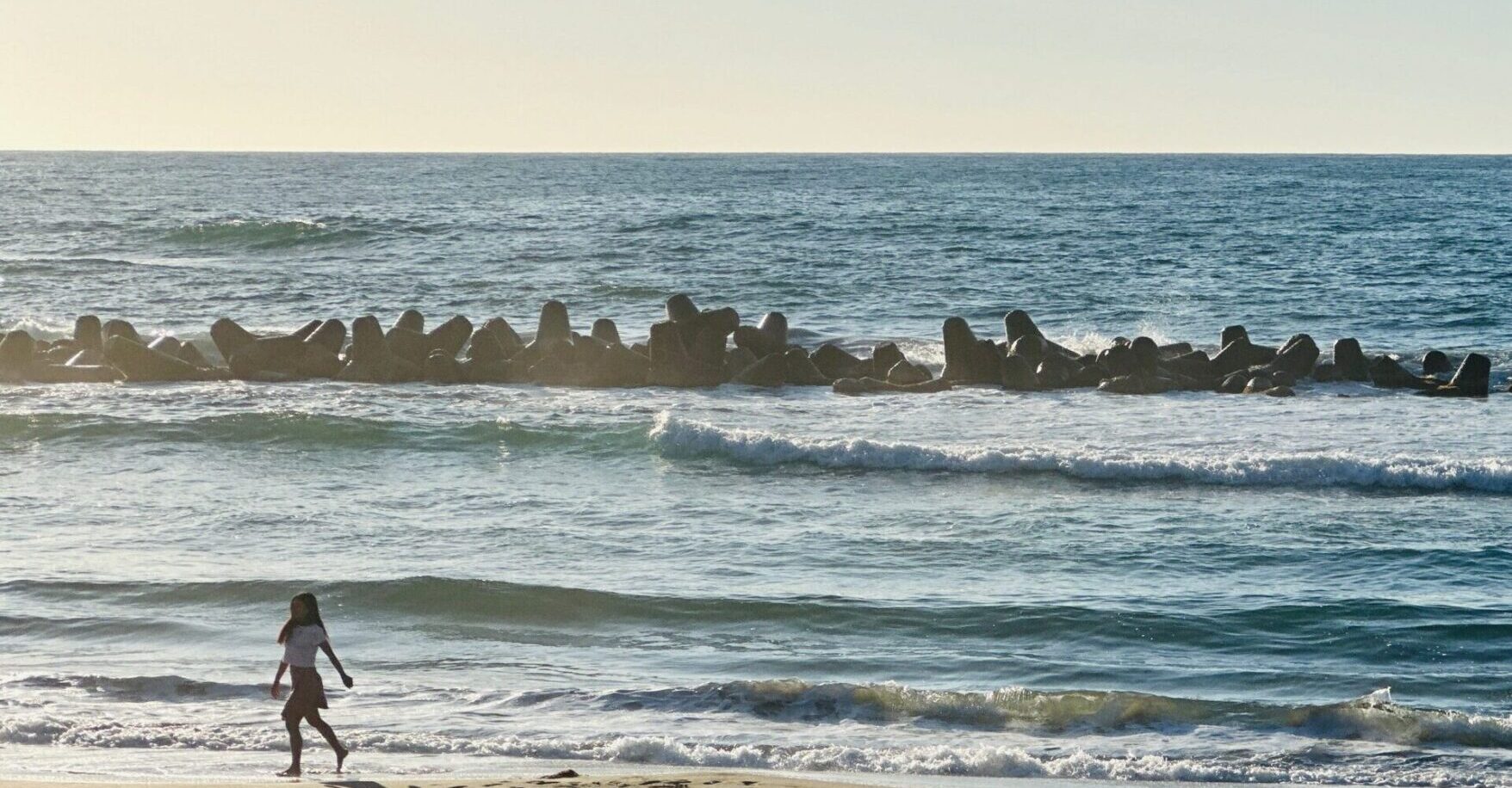 夕暮れの浜辺を歩く女性